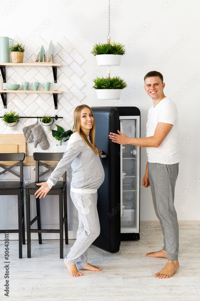 Young couple - man and woman expecting a baby, spend time in the kitchen. Awaiting the birth of a baby Young couple - man and woman expecting a baby, spend time in the kitchen. Awaiting the birth of a baby