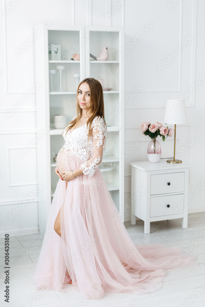 Young pretty woman with white hair waiting for baby, standing in the middle of the room in a beautiful dress. Motherhood Young pretty woman with white hair waiting for baby, standing in the middle of the room in a beautiful dress. Motherhood