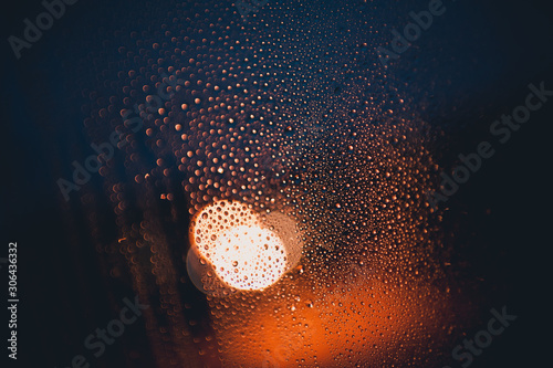 Windshield with raindrops over city traffic lights at background. Rainy day. Autumn season.