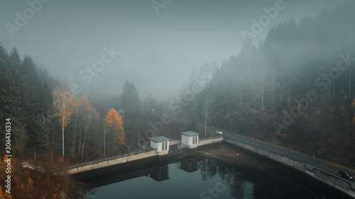 Aerial drone view of a Beautiful winter outdoor nature landscape in the mountains with pine tree forest silhouettes and colorful autumn trees in foggy clouds. Harz Mountains 