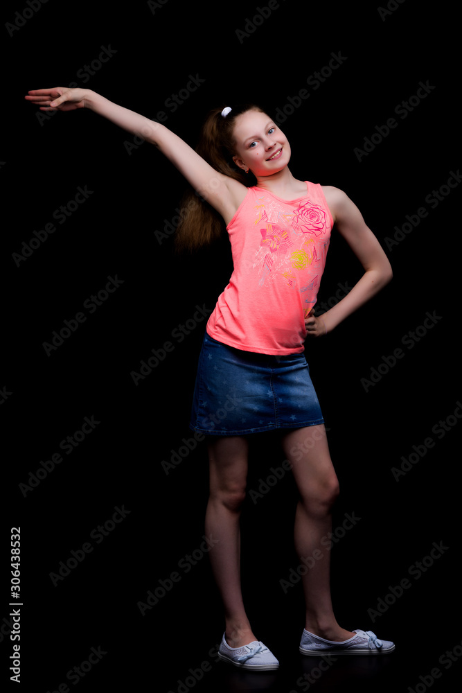 Fashionable girl teenager studio photo on a black background.