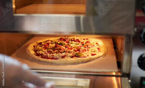 Preparing pizza at restaurant. Ready toasted oven pizza