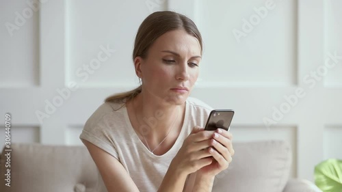 Jealous worried young woman holding phone waiting for mobile call