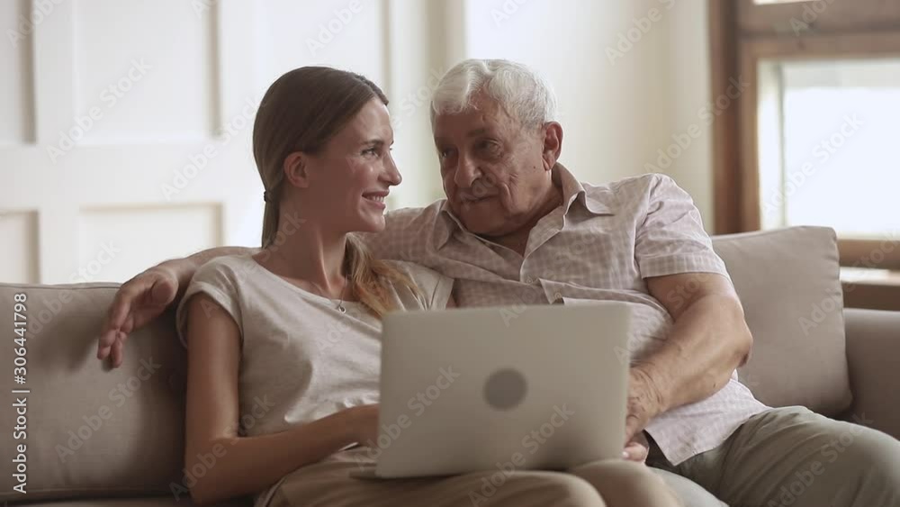 Happy senior father embracing adult daughter using laptop at home Happy senior father embracing adult daughter using laptop at home