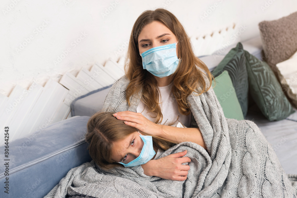 mother take care for her daughter in medical mask. recovery from illness. mother take care for her daughter in medical mask. recovery from illness.