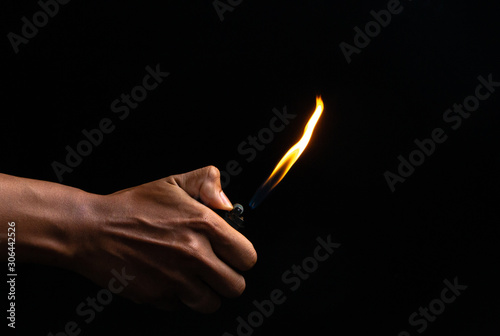 Hand holding burning gas lighters on dark background, Portable device used to create a flame, Close up