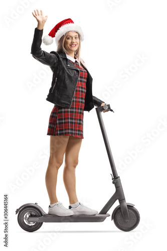 Young female on an electric scooter waving and wearing a Santa Claus hat