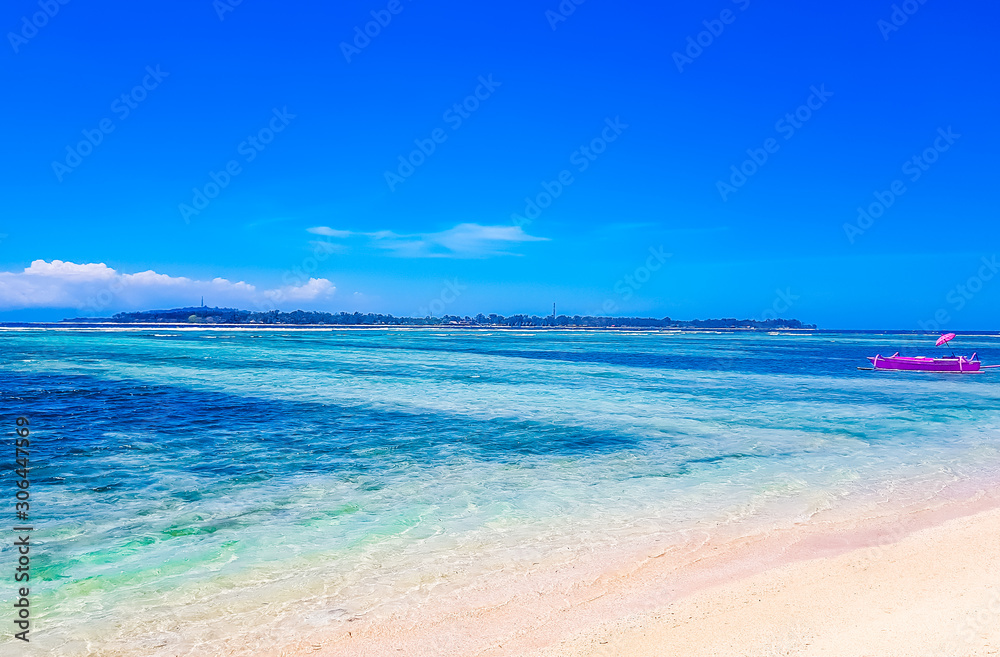 Gili Air, Lombok, Indonesia - Pink boat on the beach with umbrella next to wooden water swing in the Gili islands. Popular instagram location and holiday destination in Indonesia.