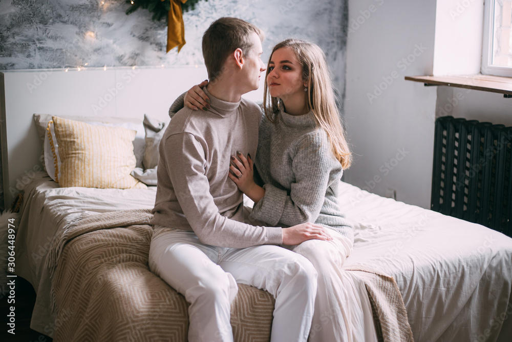 couple looking on each other near window on their bed on Christmas time couple looking on each other near window on their bed on Christmas time