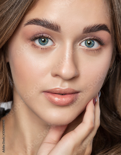 Portrait of a beautiful happy woman with long eyelashes  beautiful fresh nude make-up  thick eyebrows and with clean skin in a beauty salon. Eyelash extensions. Face close-up. Make-up concept