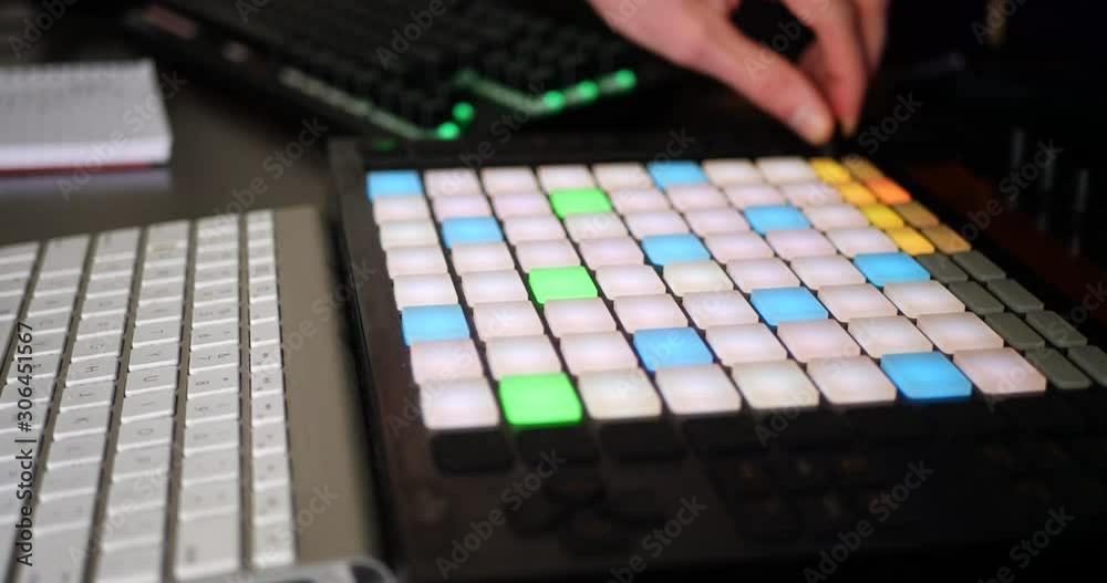 A hip hop music producer making a rap beat in his bedroom studio with a digital instrument midi controller SLIDE LEFT.