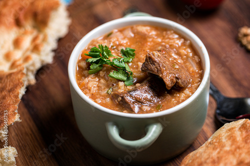 Kharcho soup with lamb meat served in a clay bowl with lavash flatbread