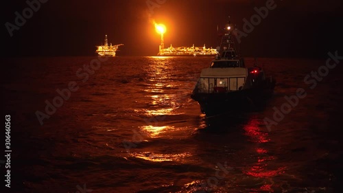 Offshore crewboat during night crewchange on offshore oilfield. FPSO tanker vessel near Oil platform Rig. Offshore oil and gas industry, sea oil production and storage photo