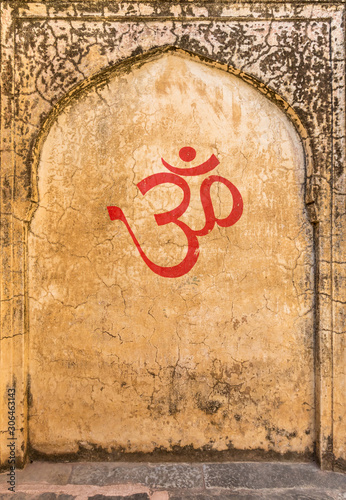 An old textured indian fort wall with an arch and OM symbol painted on the wall.