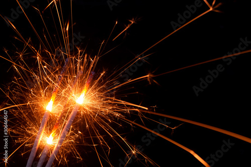 Three burning firework sparklers on black background