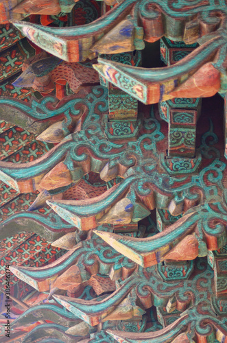 The wooden beams of a temple roof in Korea have been carved and painted in geometric patterns of blues and reds.