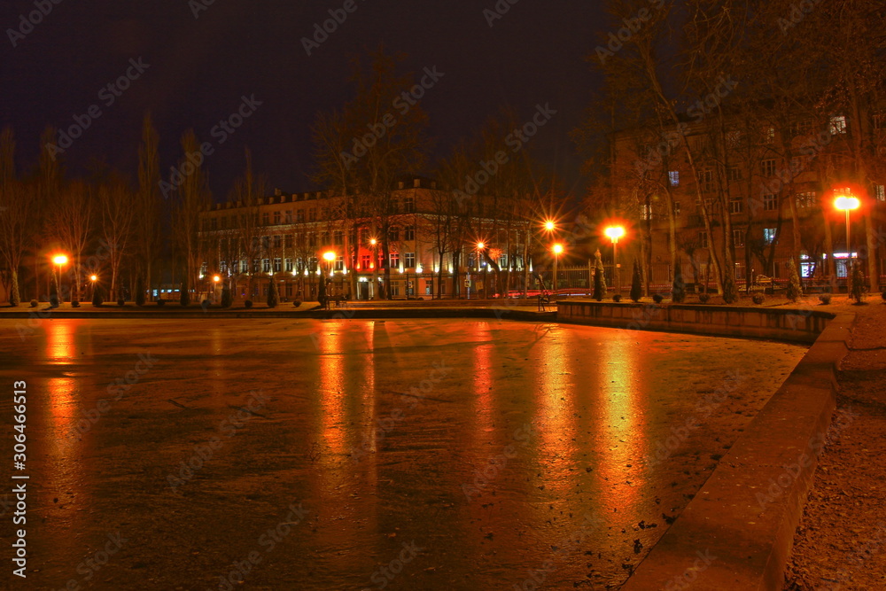 Fototapeta premium Smolensk, Russia,beautiful autumn evening in Park Lopatin Garden, ice Pond shore with glowing lanterns on houses background