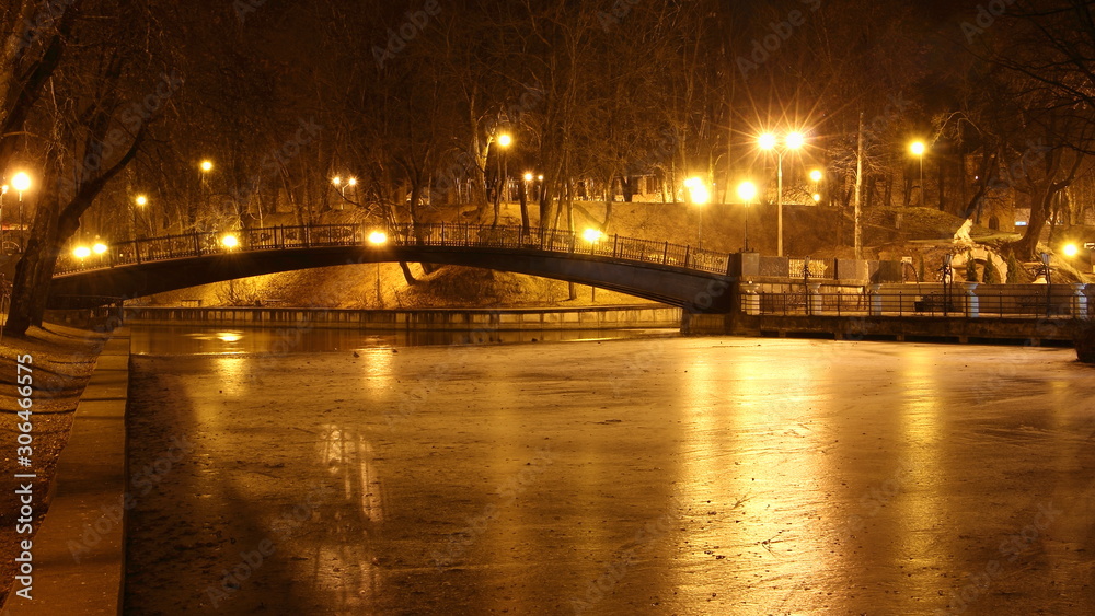 Smolensk, Russia, beautiful autumn evening in Park Lopatin Garden, Gorbaty Bridge on ice Pond with glowing streetlights
