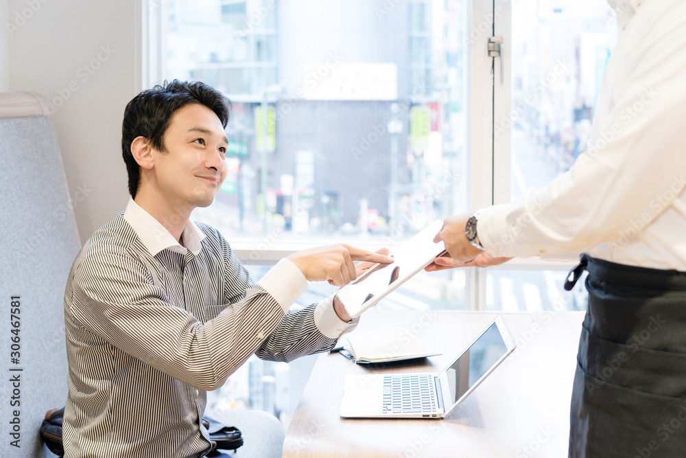 Obraz premium 飲食店でダブレット端末のメニューを見て注文する男性