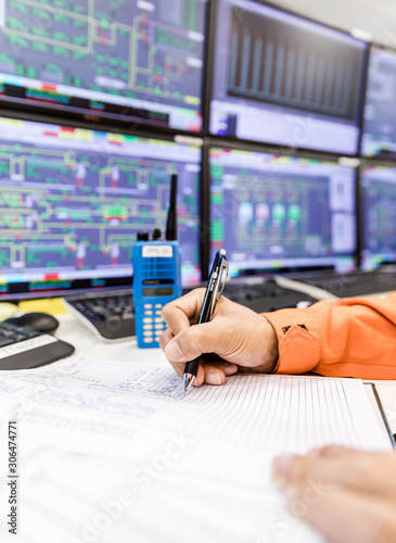 female hands with pen writing on notebook for report control panel in oil and gas process background.