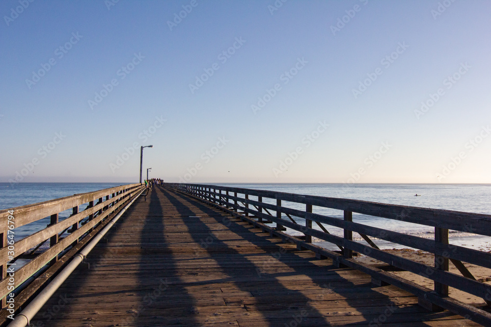 Long Wooden Pier with Shadows and Ocean During Dusk
