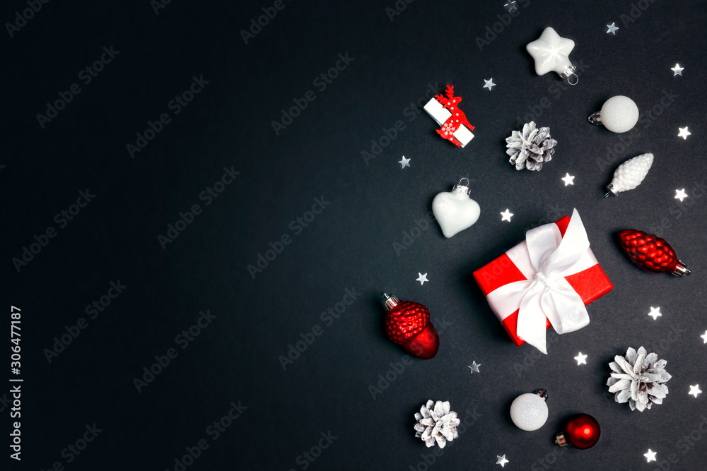 Christmas gift box with red and white decorations on black background.
