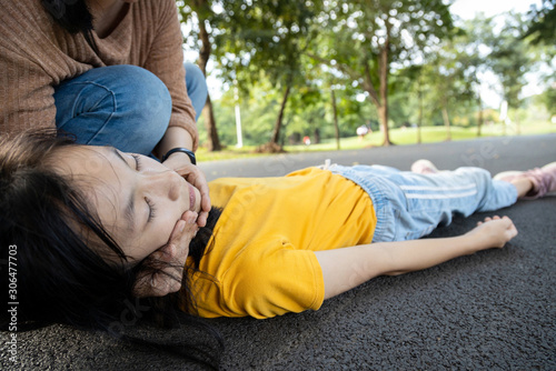 Sick teen daughter is fainted and fallen on floor while playing at park,asian mother help,take care,child girl with congestive heart failure,female unconscious lying down on ground suffer heart attack photo