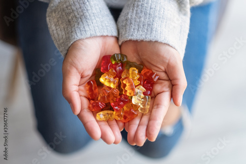 Schilderij op canvas Closeup image of a woman holding colorful jelly gummy bears in hands