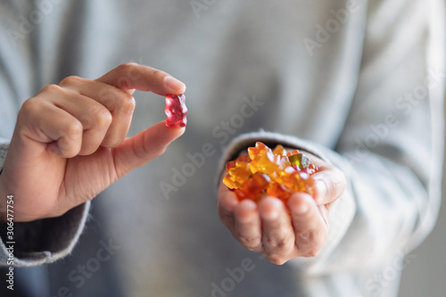 Tableau sur toile Closeup image of a woman holding and looking at a red jelly gummy bear