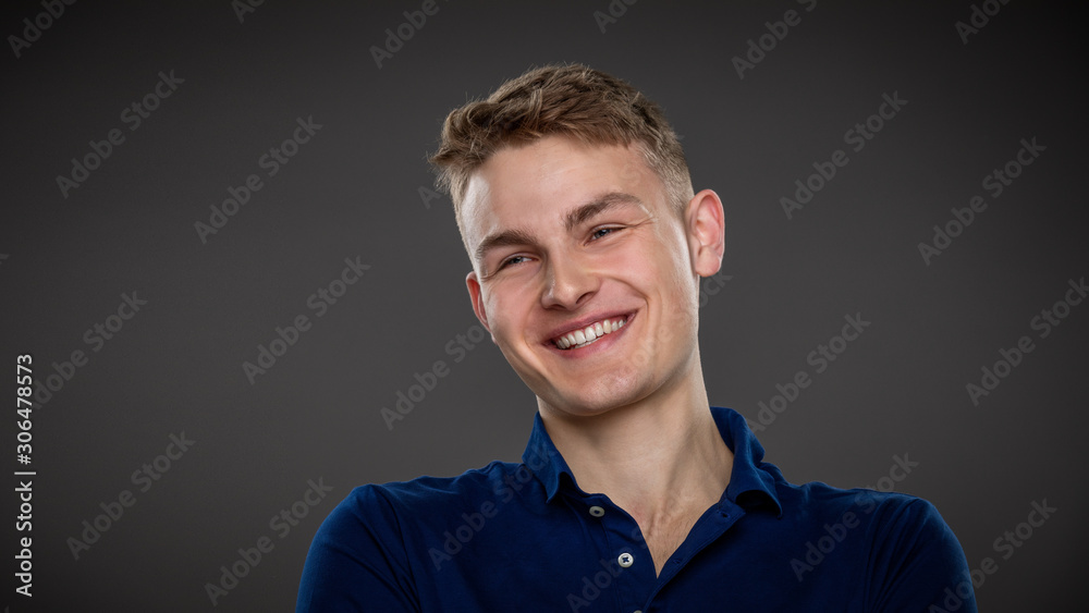 Obraz premium A handsome young man laughs as he sits in a relaxed manner