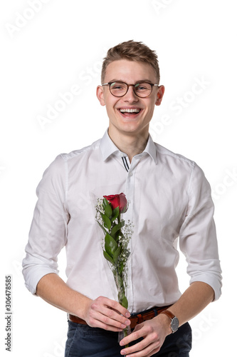 A nerdy hansome young man carries a single red rose isolated on white