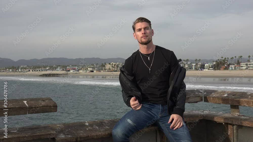 Handsome male fashion model posing on a pier Handsome male fashion model posing on a pier