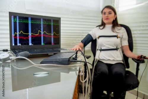 woman in polygraph test with measuring devices to know the truth, scales, hoses and measuring tubes on her body photo