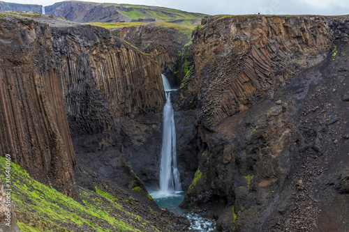 A small waterfall between unusual dark volcanic rocks