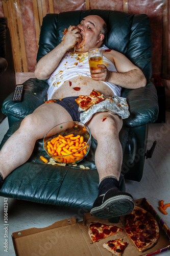 Foto Fat man eating junk food and watching television