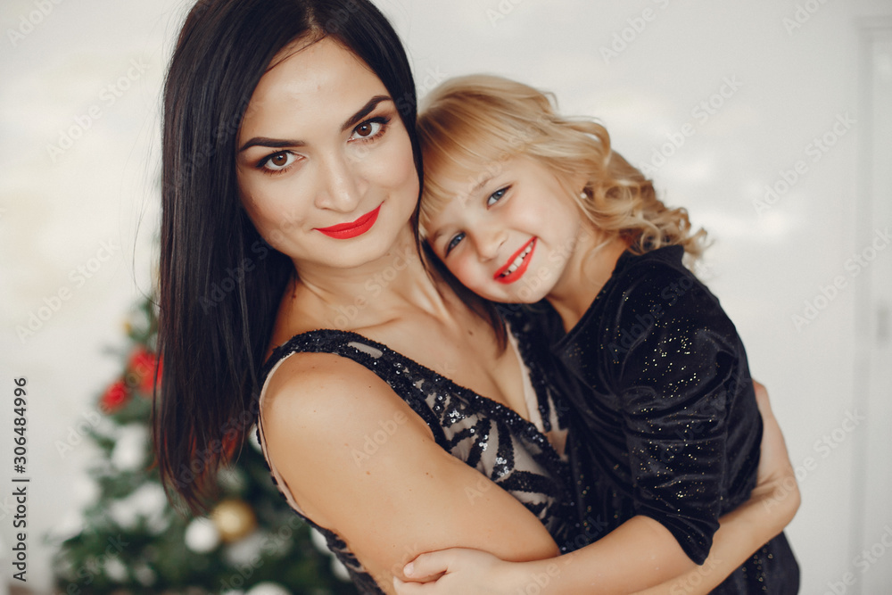 Beautiful mother in a black dress. Cute little girl near christmas tree Beautiful mother in a black dress. Cute little girl near christmas tree