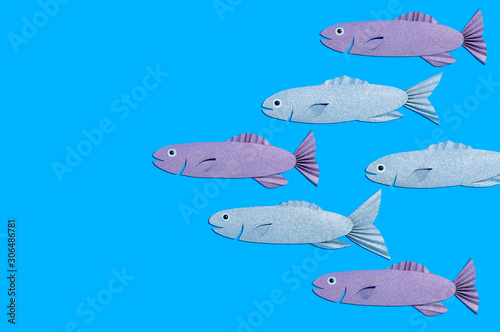 Handmade paper school of fish on blue background