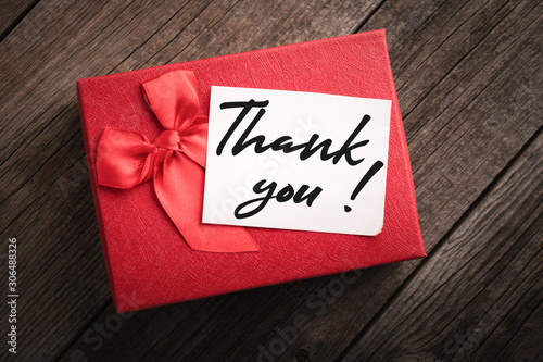 Top view red gift box and label with the words thank you on wooden background: concept of expressing gratitude and thanks