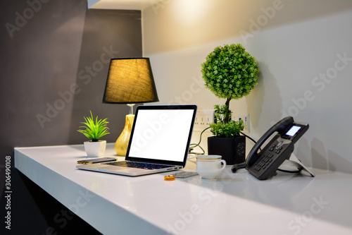 Office desk with blank screen laptop and phone