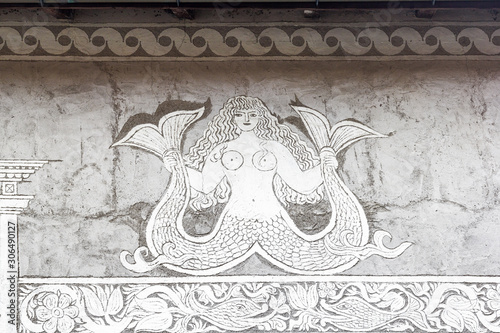 Berguen / Bravuogn, Switzerland – October 20. 2019: Traditional house facade of a mermaid by Sgraffito technique, which applies layers of plaster tinted in contrasting colours to a moistened surface. photo