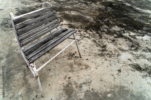 Lonely wooden bench, grungy old park bench sitting in a secluded spot. Old wooden bench on a street on a background of dirty concrete material, with free space for text input.