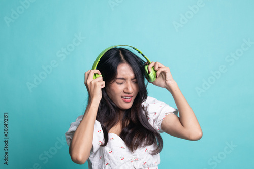 Too loud.  portrait of  young asian woman  holding  headphones and making unhappy face.