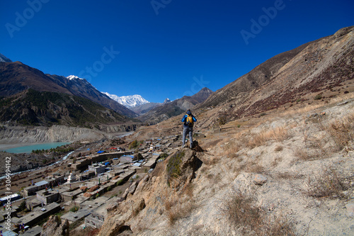 Trekker on cliff looking at view of mountain, Annapurna Conservation Area, Nepal
