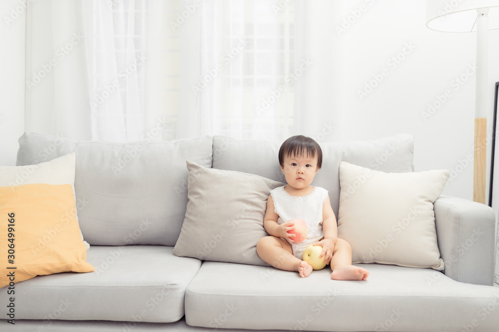 Little girl sitting and playing toy on the sofa in the living room. Kid concept.