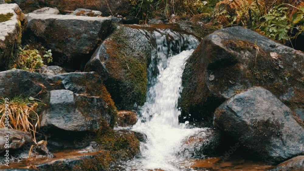 Green moss stones in the Carpathian mountains. Wonderful mountain waterfall cascade falls near large grey rocks Green moss stones in the Carpathian mountains. Wonderful mountain waterfall cascade falls near large grey rocks