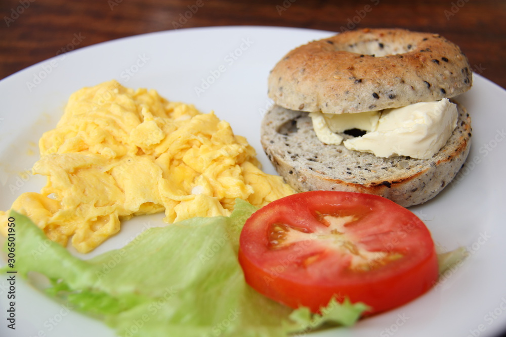 Toasted bagel with cheese, scrambled egg and salad