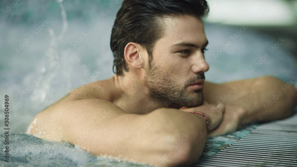 Portrait of sexy man enjoying in whirlpool bath. Handsome guy relaxing in pool