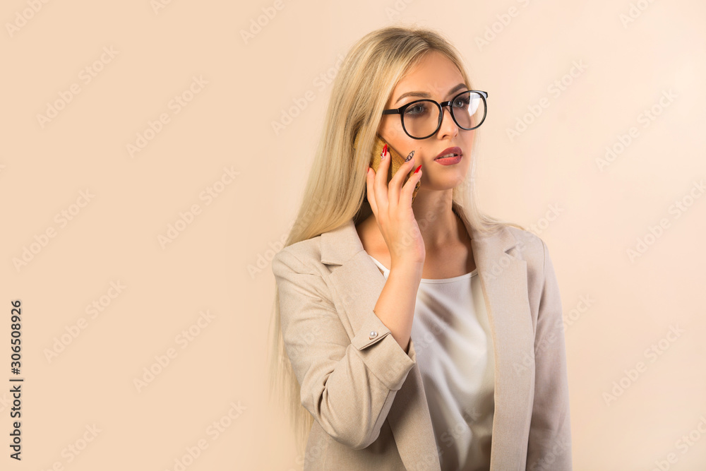 beautiful young woman in a suit on a beige background with a phone in her hand