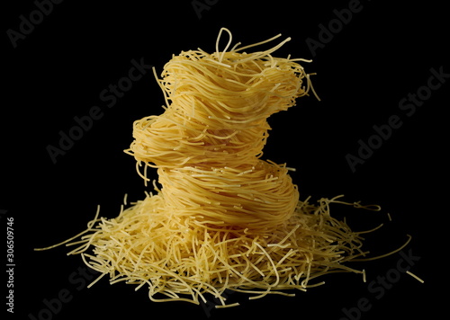 Dry, raw egg pasta noodles, isolated on black background photo