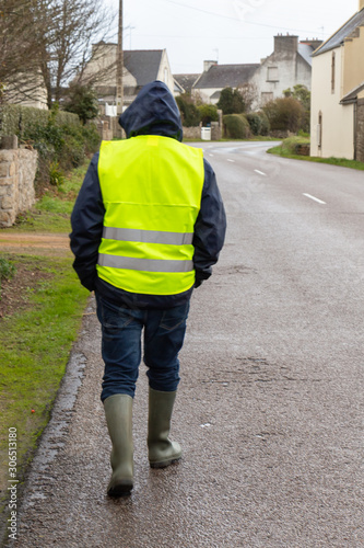 Man with yellow vest walking on the road